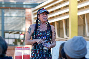 A woman holds a bag of mesquite powder while talking to students