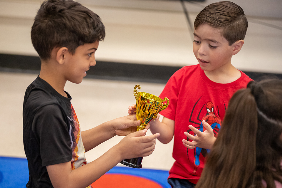 Two boys excitedly check out the trophy their class earned