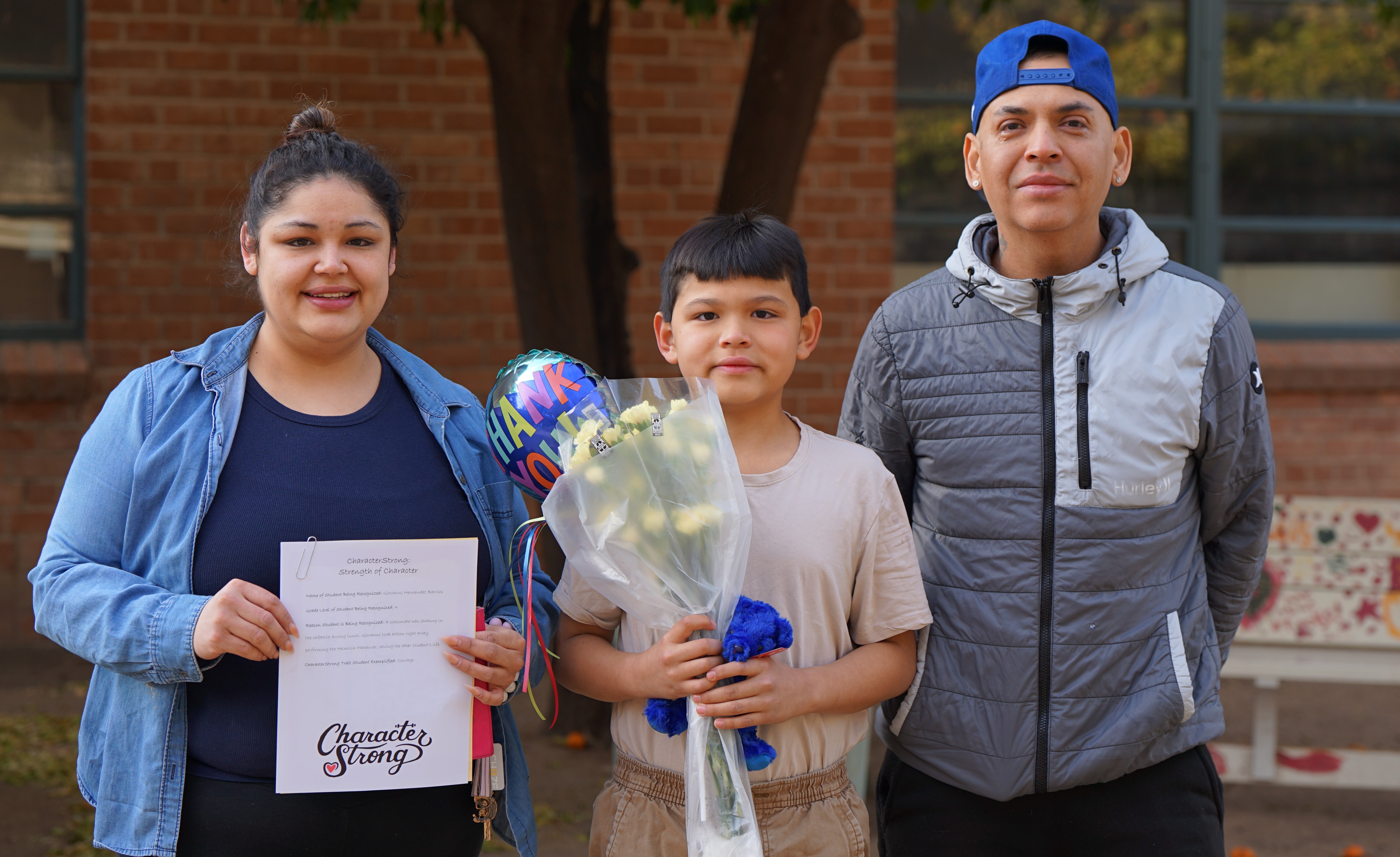 A boy holds a bouquet of flowers, next to his mom and dad