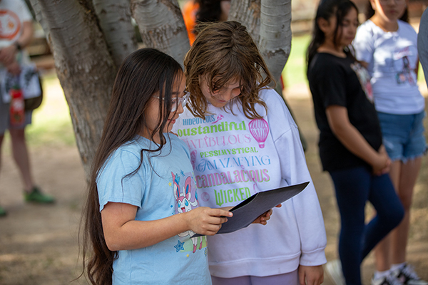 Two girls look at an award certificate one of the girls is holding