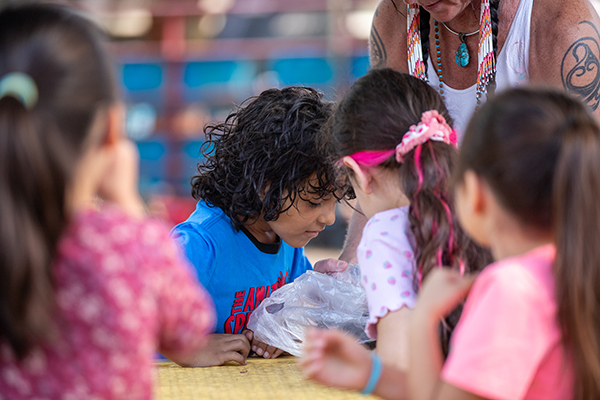 Kids gather around to look inside a plastic bag