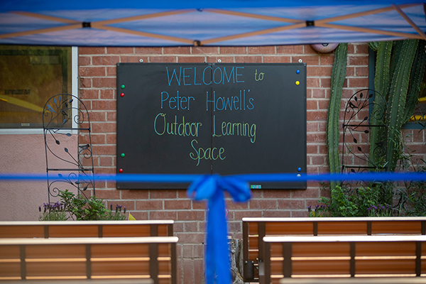 A blue ribbon hands in front of a chalkboard with the words Welcome to Peter Howell's Outdoor Learning Space