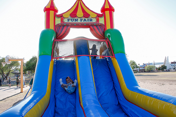 A little boy slides down a colorful bouncy castle slide