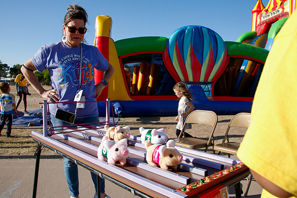 A woman looks at a game with racing stuffed pigs