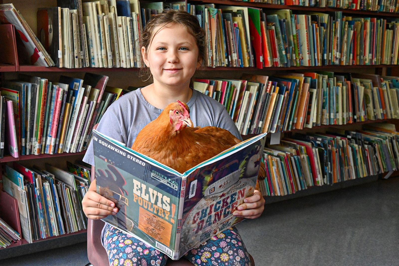 A Howell student smiles as she holds Lucy in the library.