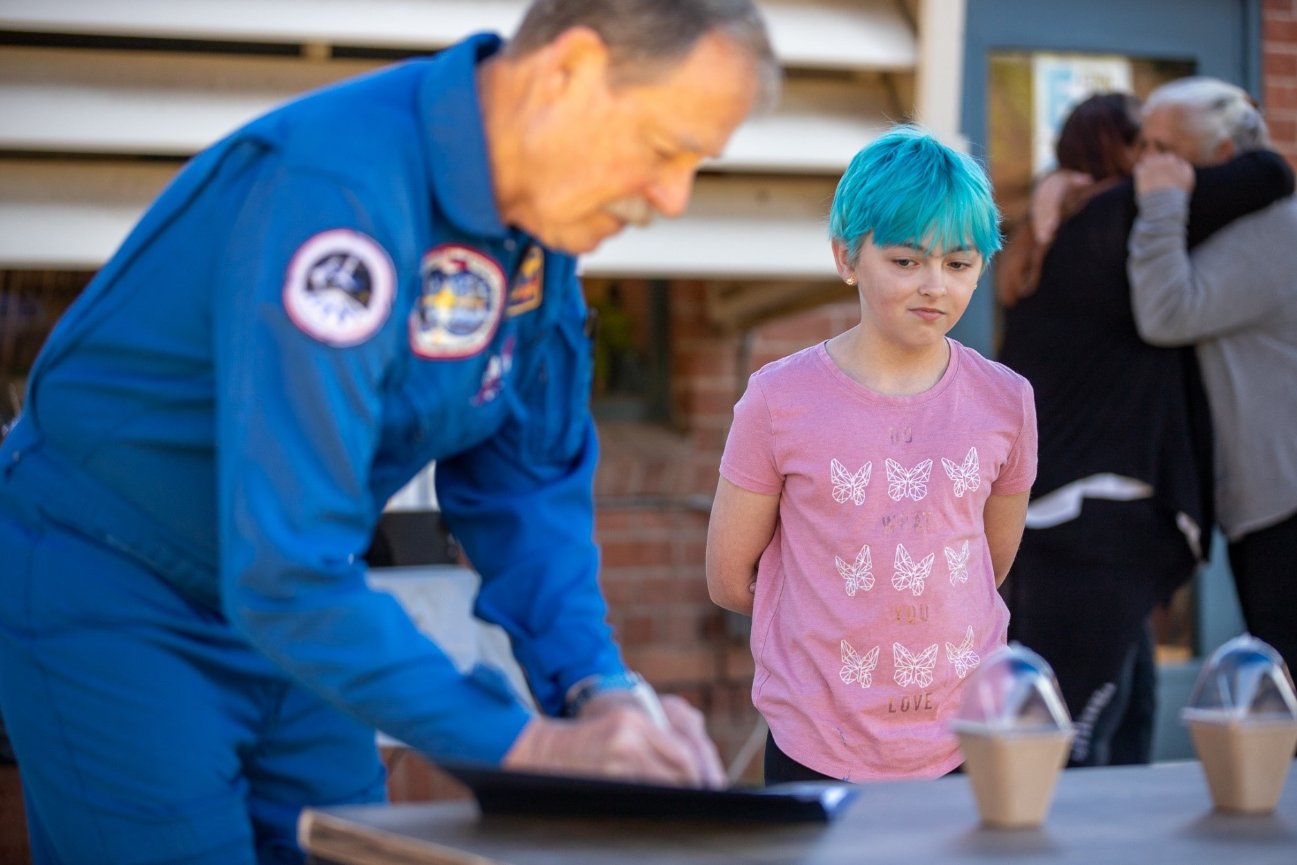 Former astronaut Hoot Gibson signs an autograph for a girl with short blue hair