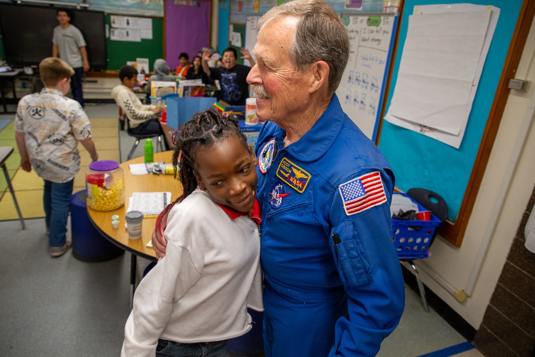 Former astronaut Hoot Gibson hugs a young girl after his presentation